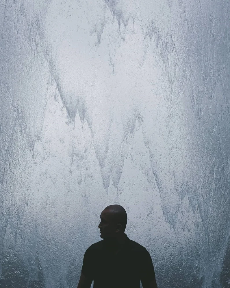 A traveler looking up at an ice-covered wall