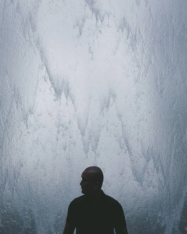 A traveler looking up at an ice-covered wall